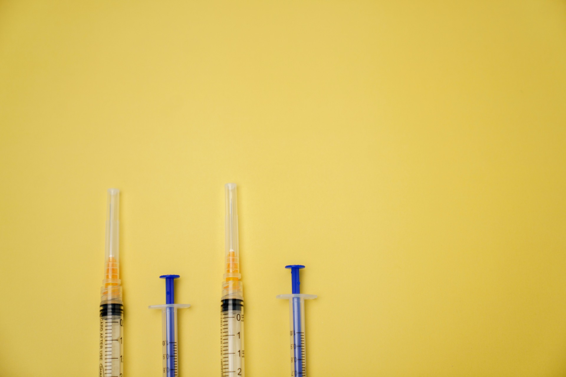 Medical Syringes Arranged Against a Bright Yellow Background for Health Concepts